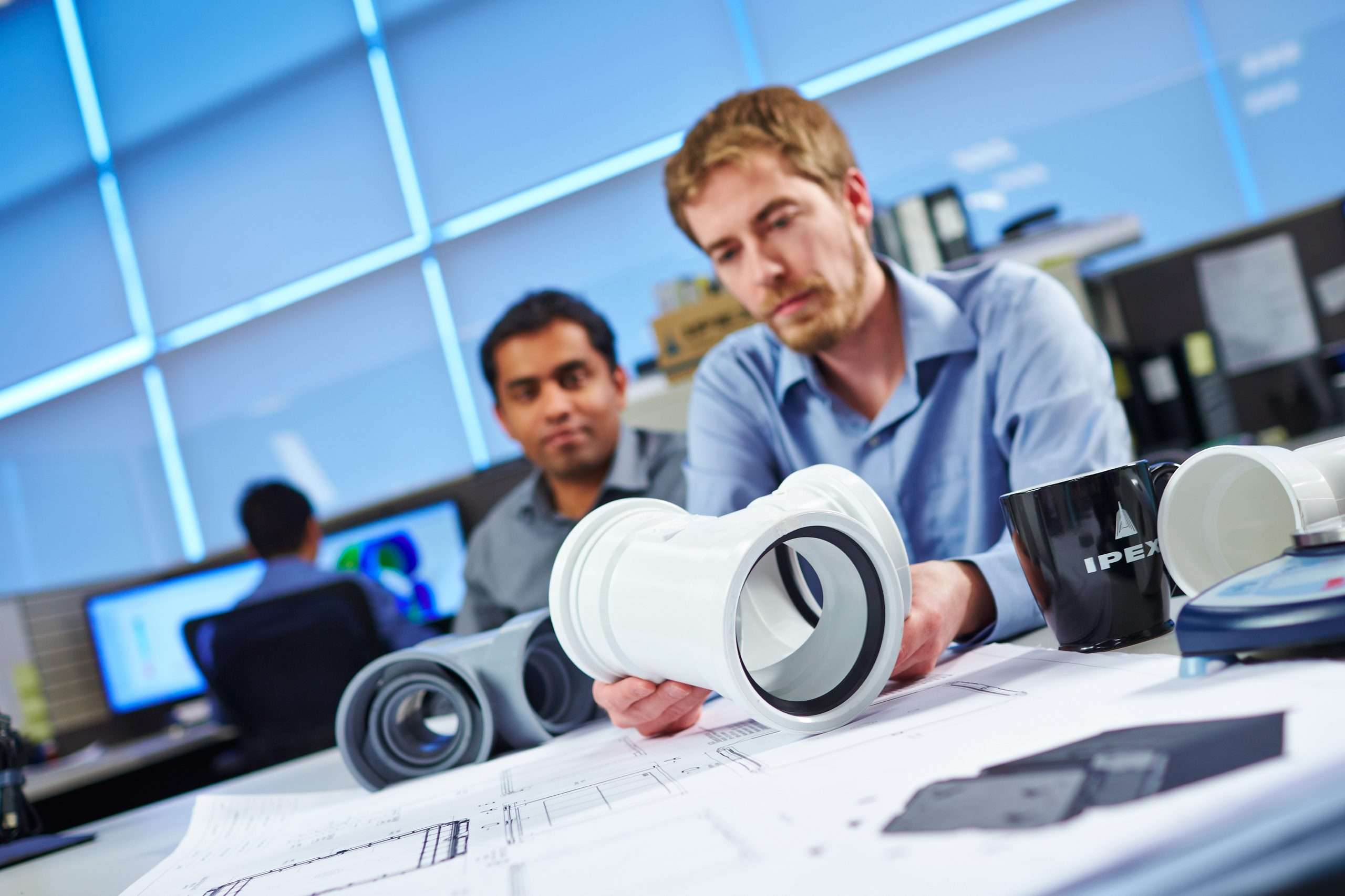 Two engineers looking at fittings and drawings