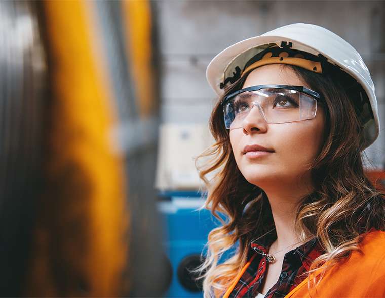 Worker in safety equipment looking upwards at the machinery