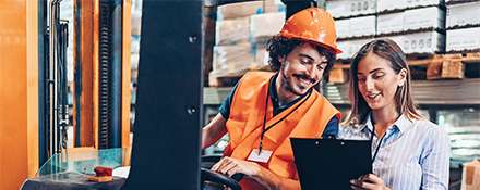 Worker on forklift and another team member looking at a clipboard